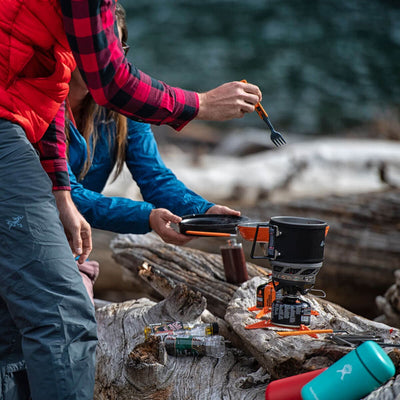 People cooking with the Jetboil MiniMo on a log next to a river