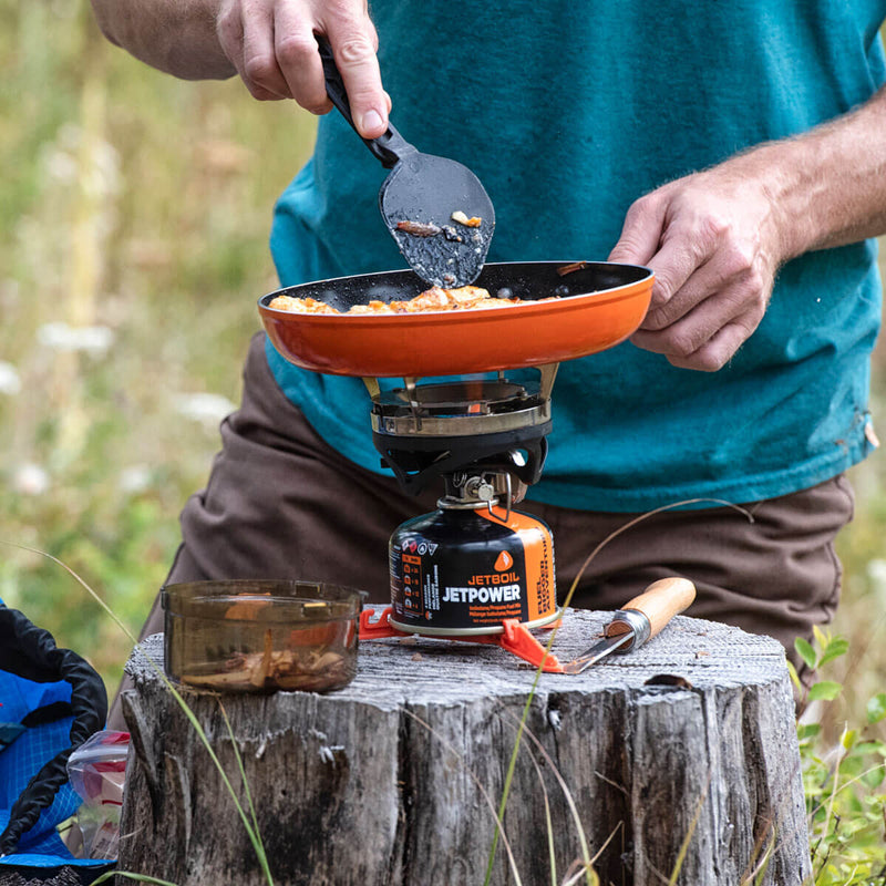 Man cooking with the Jetboil 8 Inch Ceramic Summit Skillet on a tree tunk