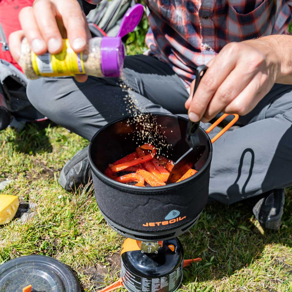 Man seasoning food inside the Jetboil 1.5L Ceramic FluxRing Cook Pot
