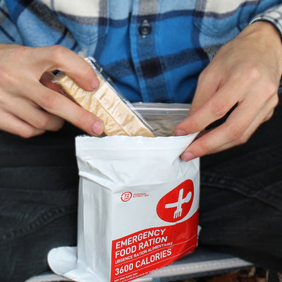 Man taking out 2 bars from 72 HRS 3600 calorie food rations package