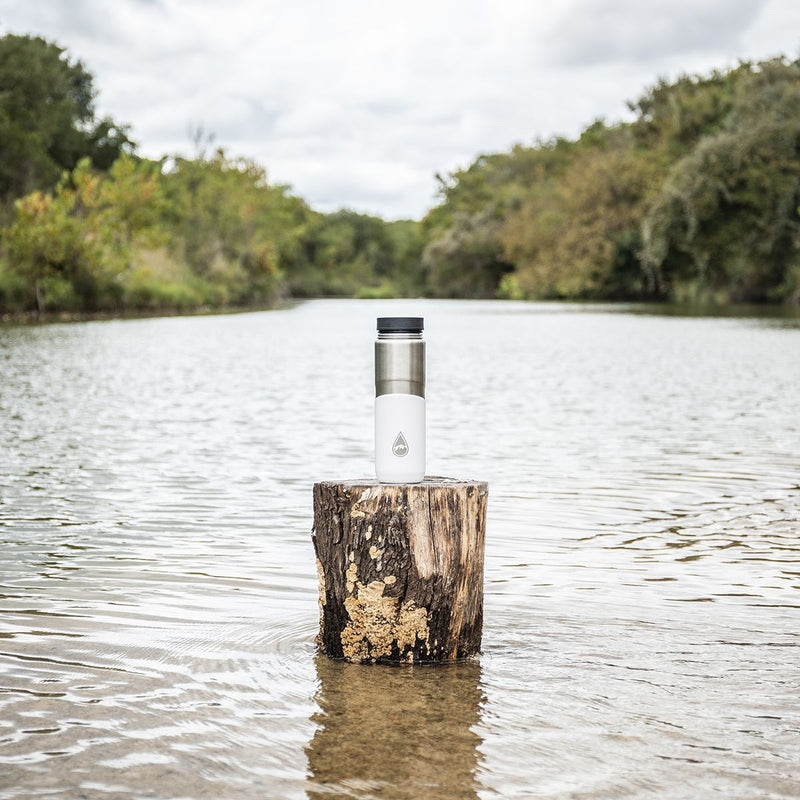 white Berkey® Lookout™ Bottle on a tree stump in a lake