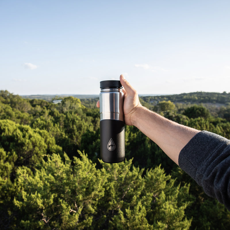 man holding black Berkey® Lookout™ Bottle with tree view
