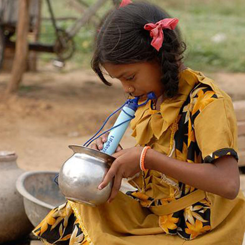 girl using lifestraw water filter and drinking from metal jug