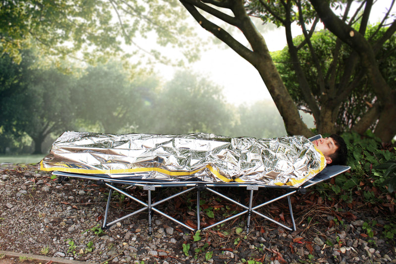 man sleeping inside 72HRS Emergency Sleeping Bag on top of camping cot